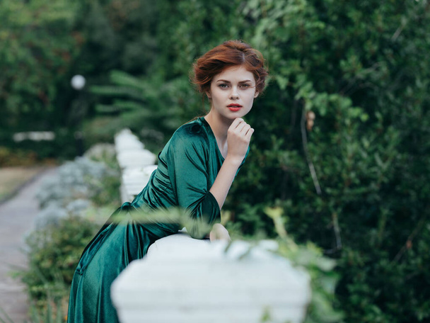 attractive red-haired woman in green dress walking lifestyle - 写真・画像