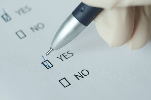 Bílý list dotazníku, odpověď "ano" je přiložena k peru. Rozmazaný obrázek. - Fotografie, Obrázek