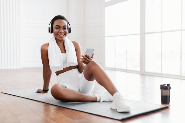 Fitness black lady listening to music during break - Foto, Imagen