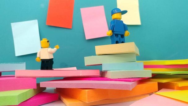 Two Lego men standing near a wall with post-its - Foto, Imagen