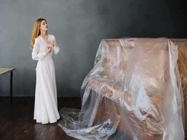vrouw in wit jurk in de buurt geketende piano romance - Foto, afbeelding