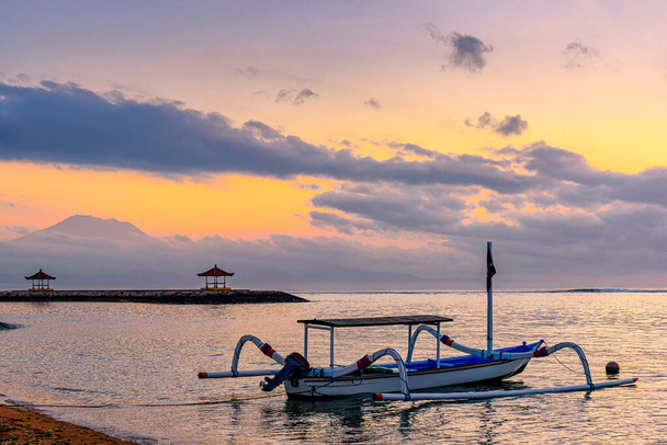 Krásný východ slunce scenérie s Jukung je tradiční balijské rybářské lodě na Karang Beach, Sanur, Bali, Indonésie.Rybářský člun na mořské pláži s východem slunce pozadí. - Fotografie, Obrázek