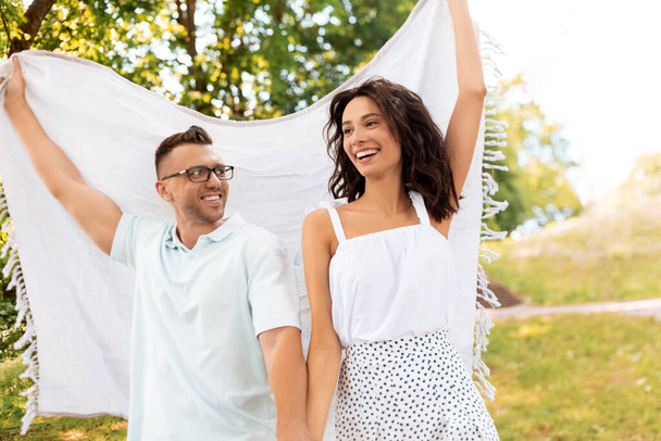 happy couple with picnic blanket at summer park - Photo, Image