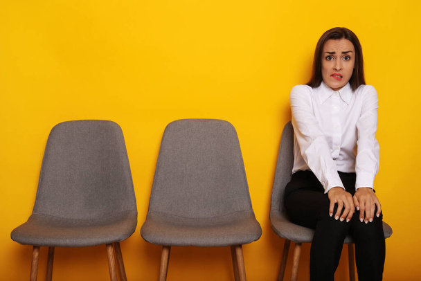 Cute stylish modern brunette woman is sitting on the chairs line on job interview appointment - Foto, Imagen