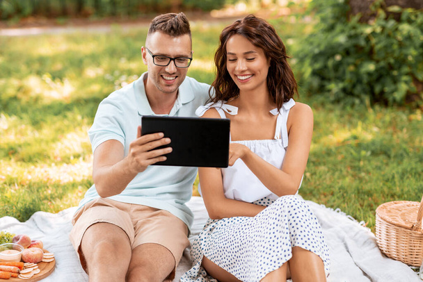 happy couple with tablet pc at picnic in park - Fotó, kép