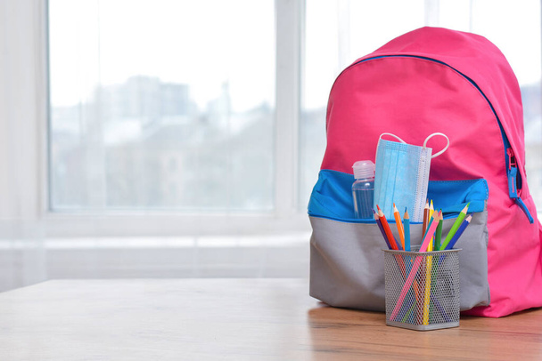 Backpack with school supplies and sanitizer and medical protective mask.Back to school and kindergarten .The beginning of the school season.Virus and disease prevention for kids.Safe Learning. - Фото, изображение