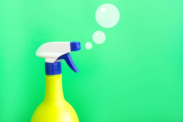 Plastikspray gelbe Flasche isoliert auf grünem Hintergrund und gemalte Seifenblasen. Flasche für Waschmittel oder Pflanzenspray - Foto, Bild