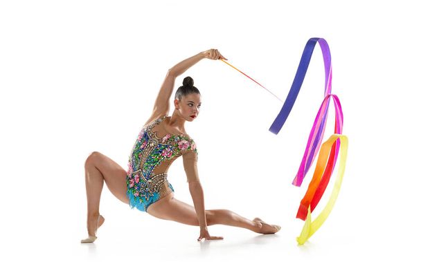 Beyaz stüdyo arka planında izole edilmiş renkli kurdeleli hareketli bir bayan ritmik jimnastikçi.. - Fotoğraf, Görsel