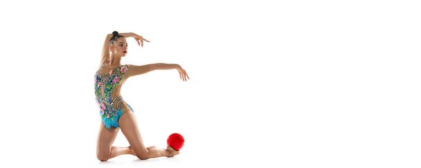 Een jonge mooie vrouwelijke ritmische gymnaste die traint met bal op witte studioachtergrond. Vlieger - Foto, afbeelding