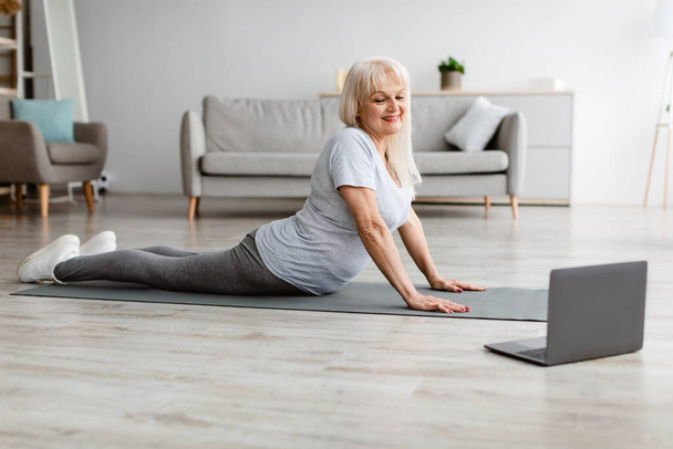 Mature woman stretching back on mat, cobra pose - Fotografie, Obrázek