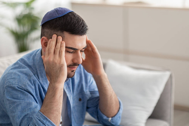 Αναστατωμένος Εβραίος που υποφέρει από πονοκέφαλο κάνοντας μασάζ στους κροτάφους του. - Φωτογραφία, εικόνα