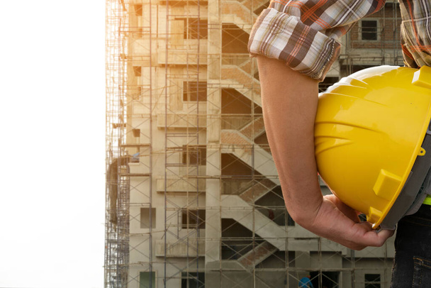 Engineer holding helmet at construction site background - Photo, Image