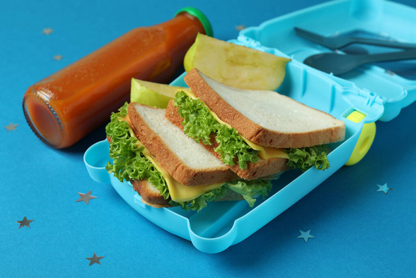 Caixa de almoço com comida saborosa no fundo azul - Foto, Imagem