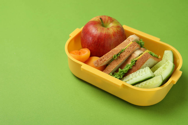 Lunch box with tasty food on green background - Photo, Image