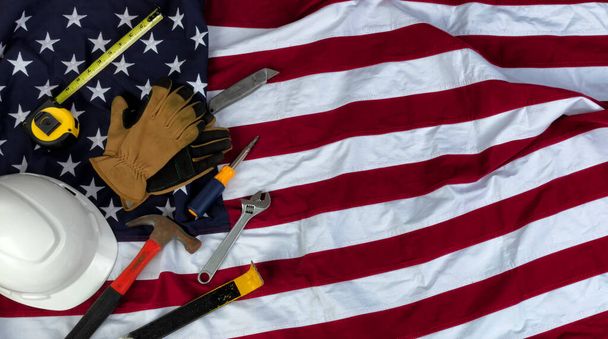 American flag with an assortment of work tools plus work gloves for US Labor Day holiday concept background  - Fotó, kép