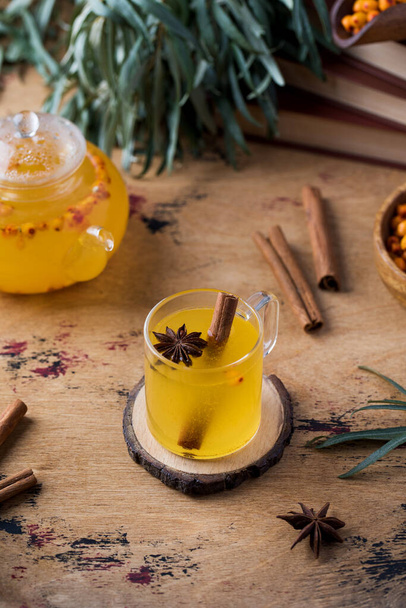 Autumn tea in a sea buckthorn mug with a cinnamon stick on a wooden background. Autumn mood. - Foto, afbeelding
