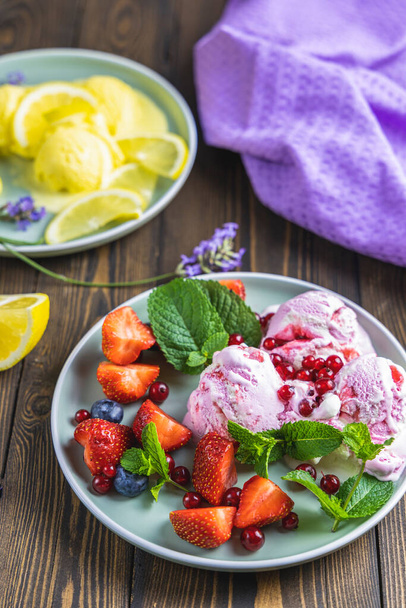 Different ice cream sorbet. Lemon and lavender, strawberry, red currant and blueberry ice cream in plates on dark wooden table surface. Dark rustic style. - Photo, image