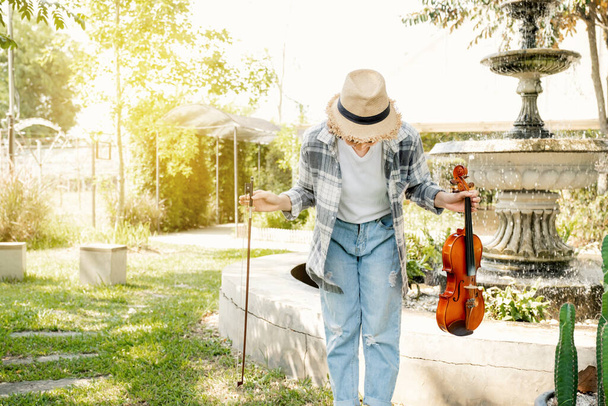 バイオリンを弾いた後の若いアジアの女性音楽バイオリニスト弓のクローズアップ肖像,心の平和と庭でリラックス. - 写真・画像