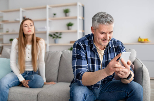 Homem sênior evitando a comunicação com sua esposa, preso no dispositivo móvel, mensagens de texto de seu amante, jogar jogos online - Foto, Imagem