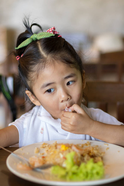 Little asian children girl eating food with spoon by herself and - Photo, Image