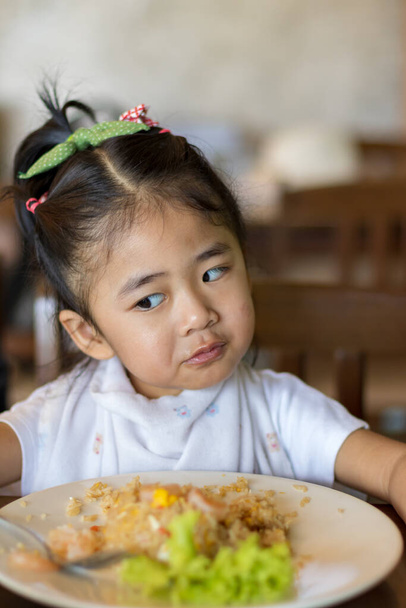 Küçük Asyalı çocuk mutlu ve onun tarafından yenilen yemekten zevk alıyor. - Fotoğraf, Görsel