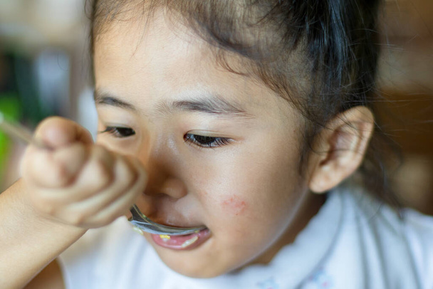 アジア系の女の子が一人で食べ物を食べていて - 写真・画像