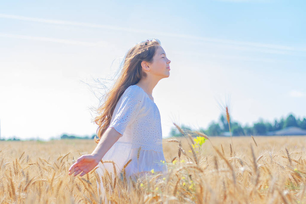 heureuse fille mignonne debout parmi le champ de blé par une journée ensoleillée - Photo, image