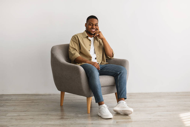Successful African American Man Posing Sitting In Chair, Gray Background - Фото, изображение