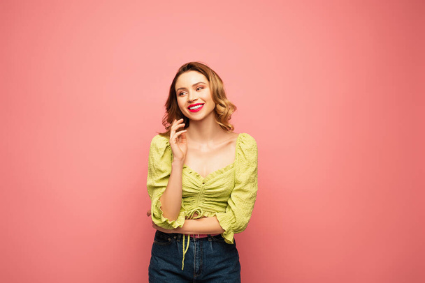 cheerful woman in green blouse smiling isolated on pink  - Fotó, kép