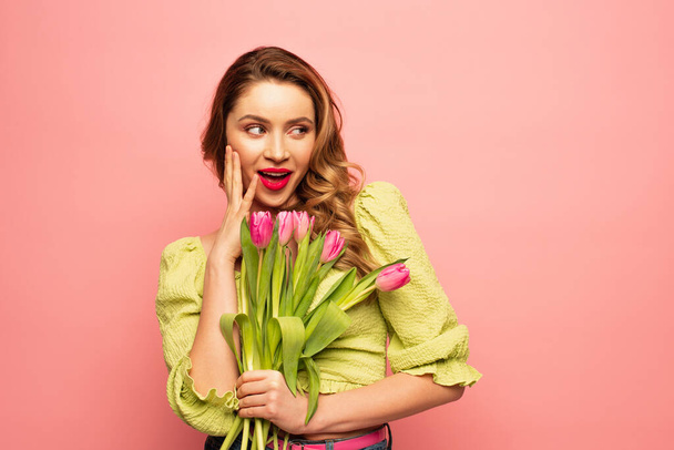 amazed woman holding bouquet of tulips isolated on pink - Zdjęcie, obraz