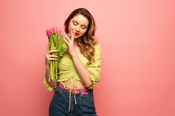 joyful woman smelling tulips isolated on pink - Foto, afbeelding