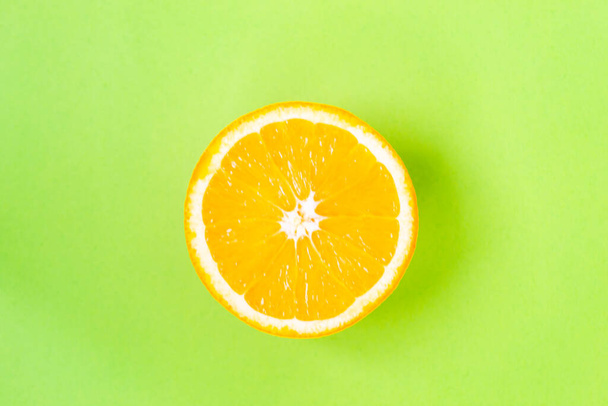 Top view of one orange round fruit on bright green background. Rich citrus texture. Copy space. - Zdjęcie, obraz