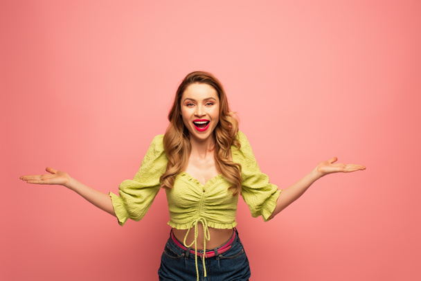 cheerful woman with outstretched hands and open mouth isolated on pink - Foto, imagen