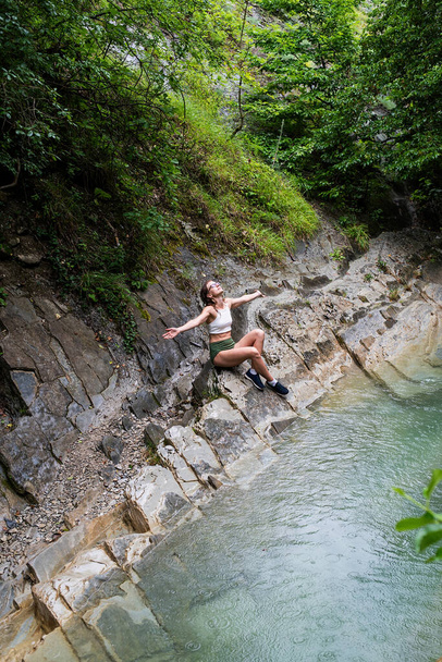 夏の旅行。ハイキングだ。若い幸せな女性は、山の川に座って、自然を楽しんで. - 写真・画像