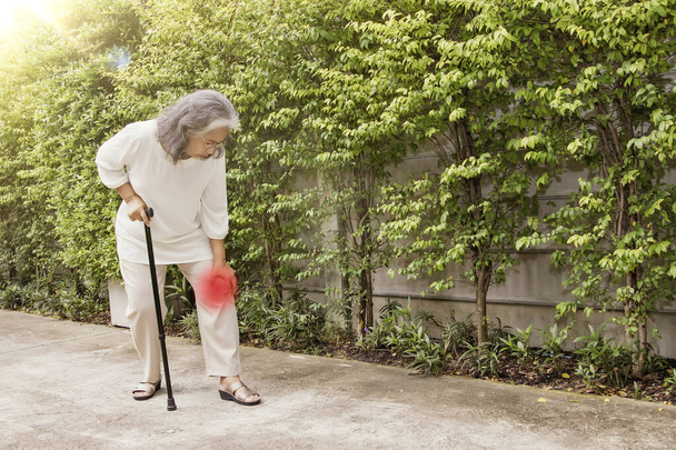 Idős ázsiai nő masszírozza a bal térde osteoarthritis séta közben: Térd sérülés Gyulladás gyakoribb az idősek: Egészségügyi koncepció: Szelektív Focus - Fotó, kép