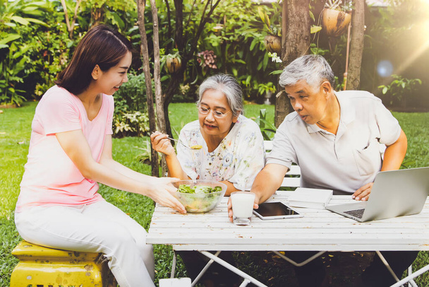 La famille était heureuse sur la table à manger située au milieu du jardin : Prendre soin de manger et de vivre pour les personnes âgées concept - Photo, image