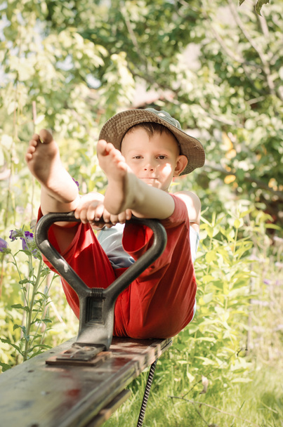 Симпатичный деревенский мальчик сидит в саду
 - Фото, изображение