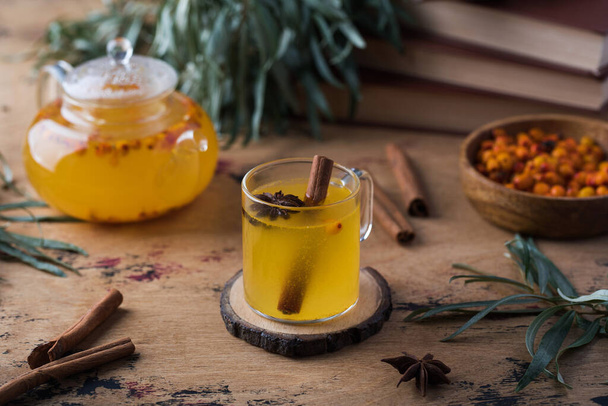 Autumn tea in a sea buckthorn mug with a cinnamon stick on a wooden background. Autumn mood. - Foto, Imagen