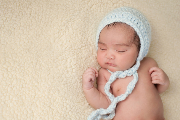 Спящий новорожденный несет светло-голубой капот
 - Фото, изображение
