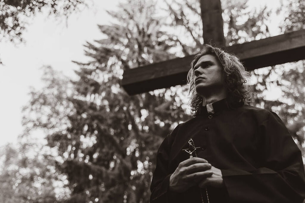 Христианский священник с крестом на кладбище. - Фото, изображение