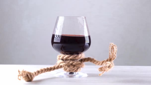 Sklenice na víno je přivázaná provazem. Koncept závislosti na alkoholu. - Záběry, video