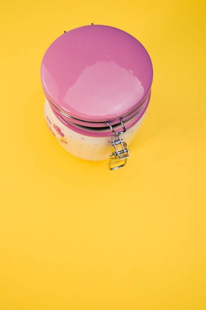A plastic canister for tea or coffee isolated on a yellow background - Zdjęcie, obraz