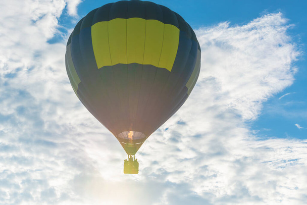 Μπαλόνι θερμού αέρα και μπλε ουρανός, ήλιος, λευκό νέφος.Μπλε κίτρινο αερόστατο θερμού αέρα στον αέρα το βράδυ του καλοκαιριού. - Φωτογραφία, εικόνα