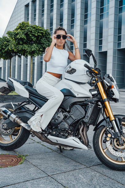 Motociclista femenina de moda sentada en motocicleta moderna en la ciudad - Foto, Imagen