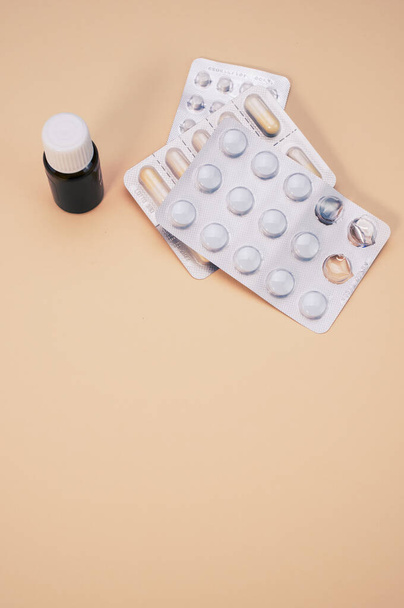 Dwa opakowania z tabletkami i mała fiolka wyizolowana na beżowym tle - Zdjęcie, obraz