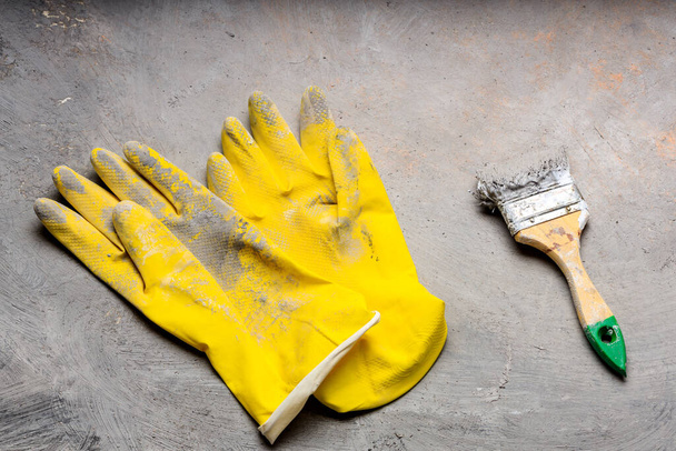 λαστιχένια κίτρινα γάντια και πινέλο μπογιάς σε γκρι φόντο. εργαλεία ζωγραφικής - Φωτογραφία, εικόνα