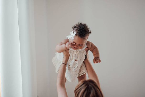 mixte race bébé fille dans sa mère mains - Photo, image