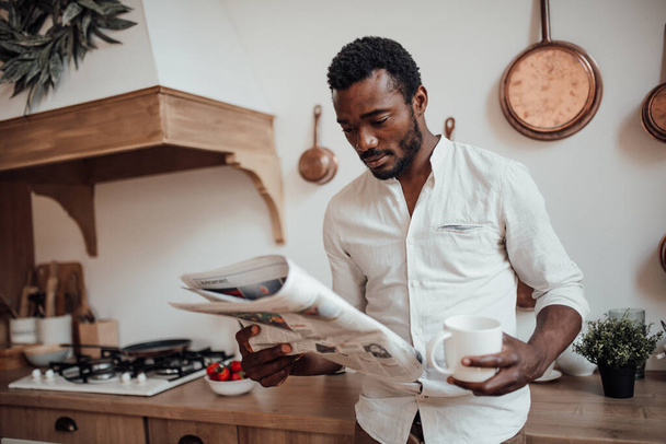 homme afro-américain en chemise lecture journal et boire du café - Photo, image