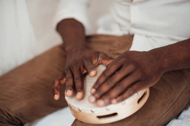 Hands of african american man holding musical instrument tambourine - Foto, Bild