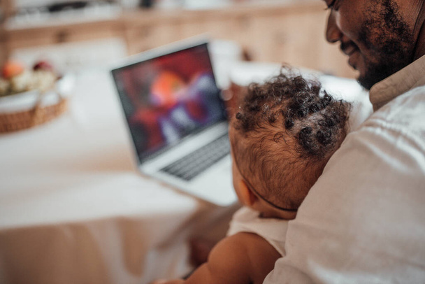бізнесмен працює з дому на ноутбуці, тримаючи дочку
 - Фото, зображення